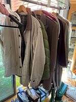 Full rack of six coats on hangers showing assortment of styles and colors