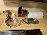 Full view of the lot showing all items including bread box, bakeware, espresso pot, rolling pin, cookie cutters, and knife block with knives