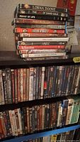 Shelf showing arranged DVDs with various movie titles and some partially visible titles along bottom row