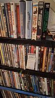 Three shelves filled with assorted DVDs and VHS tapes, showing titles and variety in formats.