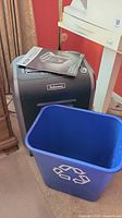 Wide view of Fellowes shredder with user manual on top and blue recycle bin in front