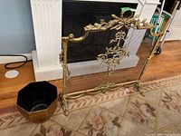Metal freestanding fireplace screen and metal bin shown by fireplace on floor