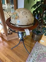 Photo of the entire globe on metal stand with tripod legs and wooden circular table, showing full setup and size