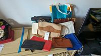 Overview of all bags including leather handbags, clutches, canvas tote bags, and insulated lunch bag arranged on a cabinet.