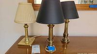 Three small accent lamps displayed, two with black shades and one with cream pleated shade, showing overall appearance and size comparison.