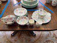 Full view showing stacked small plates/coasters, soup bowls, serving plate, teacups, and egg cups all with Minton Haddon Hall floral pattern.