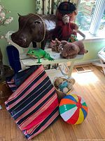 Overview of lot showing leather-like hippo, motion sensor frog, assorted plush animals, inflatable cushion bag and beach ball