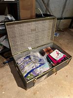 Open vintage trunk filled with assorted linens and blankets inside a basement setting