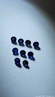 Nine round royal blue sapphires arranged on a flat light surface, showing size and color consistency.
