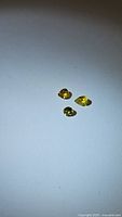 Three bright canary yellow sapphires on a white background, showing clarity and color under light from a distance.