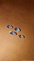 Four marquis cut aquamarine gemstones laid out on a brown textured surface.