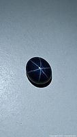 Oval cut blue star sapphire showing a distinct 6-ray star pattern on surface under light.