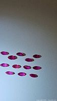 Thirteen natural marquis cut rubies arranged on white background showing uniform deep red color and transparency