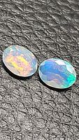 Two faceted oval Ethiopian opals showing multicolored flashes on a textured black background.
