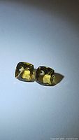 Two natural golden citrine cushion cut gemstones placed side by side on a flat surface, showing their color and cut under natural light.