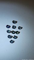 Ten small round cut sapphires in various blue-green colors laid out on white background.