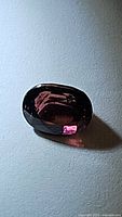 Close-up image of the oval cut purple pinkish tourmaline gemstone showing color and clarity under light.