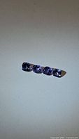 Four cushion cut blue Tanzanite gemstones arranged in a row on white background in natural light, showing color and shape.
