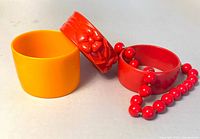 Three bangles and red bead necklace displayed