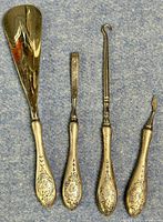 Set of four sterling silver manicure tools including shoehorn laid out on cloth background