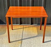 Full view of the rectangular rosewood table with four tapered legs, showing natural wood grain and warm polished finish
