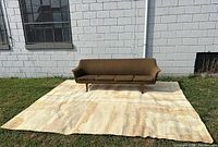 Rug laid flat outdoors with brown sofa at one end