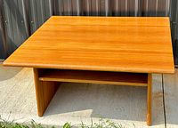 Front view of teak coffee table showing rectangular top and lower shelf