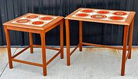 Two teak nesting tables side by side with decorative tile tops, showing style and size difference