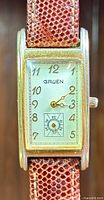 Front view of the rectangular curved Gruen Curvex watch face showing silver dial, Arabic numerals, subdial, and gold-tone hands with brown leather strap.