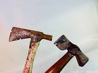 Two vintage shingling hatchets with metal heads and wooden handles, showing signs of rust and usage.