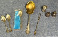 View of the full set including spoons, cheese fork, and three spice shakers on blue fabric background