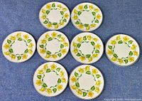 Eight Wedgwood Kingcup pattern bread and butter plates arranged in two rows on blue surface.