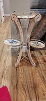 Full view of stand showing three curved legs and two lower trays folded down