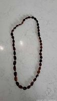 Dark cognac oval bead amber necklace laid flat on countertop