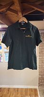 Front view of dark green polo hanging on hanger