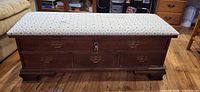 Full view of chest closed showing upholstered top, brass pulls, lock