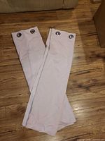 Two light pink curtain panels folded with grommet tops visible