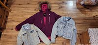 Purple parka centered with two denim jackets laid out