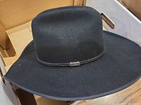Overall view of black wide-brim felt hat with braided band
