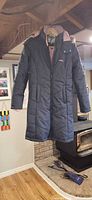 Front view of gray quilted coat with pink lining and pockets
