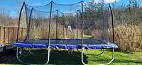 Full side view showing trampoline frame, legs, blue pad, safety net