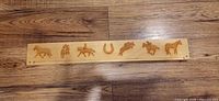 Full view of wooden ribbon display bar with engraved horse motifs