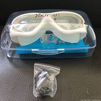 Swim goggles in original clear plastic case with spare nose pieces in a small plastic bag.