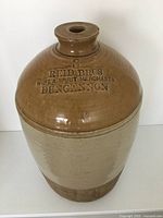 Front angled view of the stoneware jug showing the Reid Bros embossed lettering, glaze color variations, and overall shape.