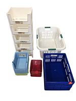 Lot of five plastic storage baskets shown together: two white stackable baskets in vertical rack, white collapsible laundry basket with green handles, large blue basket, small red basket, and four small blue baskets.