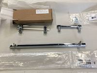 Three cabinet handles laid out flat showing size comparison and mounting hardware, includes packaging with label 'Cabinet 12" Mod Hex Pull'.