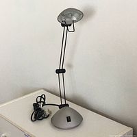 Full view of aluminum alloy desk lamp standing on table showing adjustable arm and lamp head