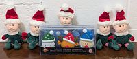 Photo of 5 Christmas elf plush toys and the boxed set of 3 flashing LED nose ornaments in the middle, showing full lot contents.