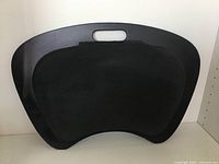 Front side of black Handstands laptop lapmat showing cushioned textured surface and built-in handle.