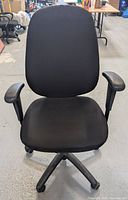 Front view of black ergonomic office chair with fabric upholstery, high back and adjustable arms.